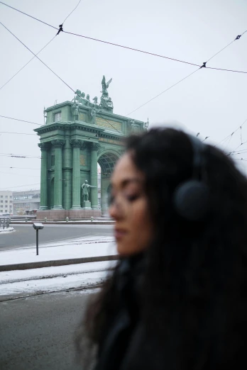 a woman walking down a street with headphones on, pexels contest winner, berlin secession, on the frozen danube, arch, still from a music video, saint petersburg