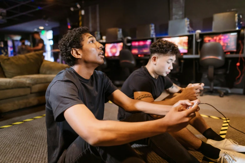 two young men sitting on the floor playing video games, pexels, a busy arcade, avatar image, black teenage boy, server in the middle