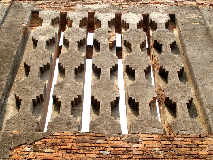 a window on the side of a brick building, by Bradley Walker Tomlin, conceptual art, sukhothai costume, jagged blocks of stone, symmetrical patterns, complex ceiling