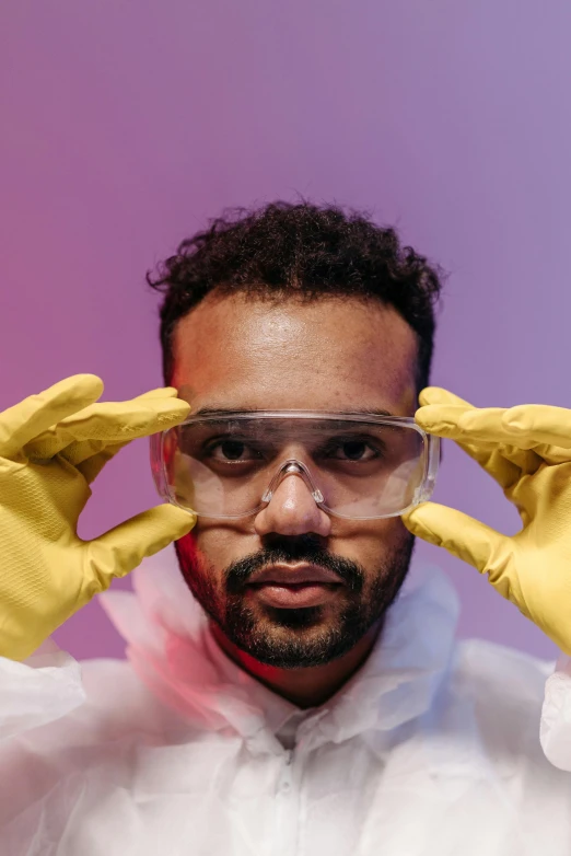 a man in a white lab coat and yellow gloves, inspired by Ismail Gulgee, pexels contest winner, afrofuturism, goggles on forehead, glass labware, mixed race, looking at viewer
