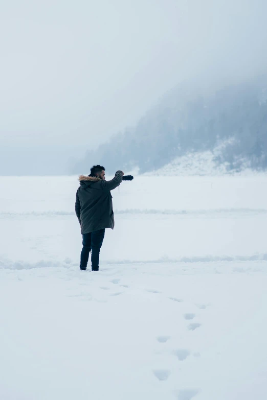 a woman walking across a snow covered field, a picture, inspired by Henri-Julien Dumont, unsplash, near lake baikal, pointing at the camera, production photo, man?