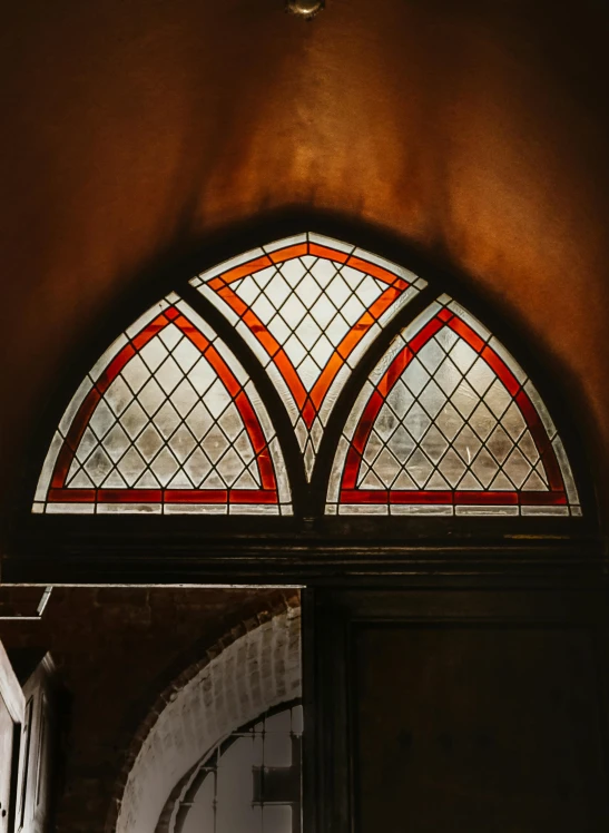 a bride and groom standing in front of a stained glass window, inspired by Pieter de Hooch, trending on unsplash, red and brown color scheme, curving geometric arches, close-up shot taken from behind, interior of a victorian house