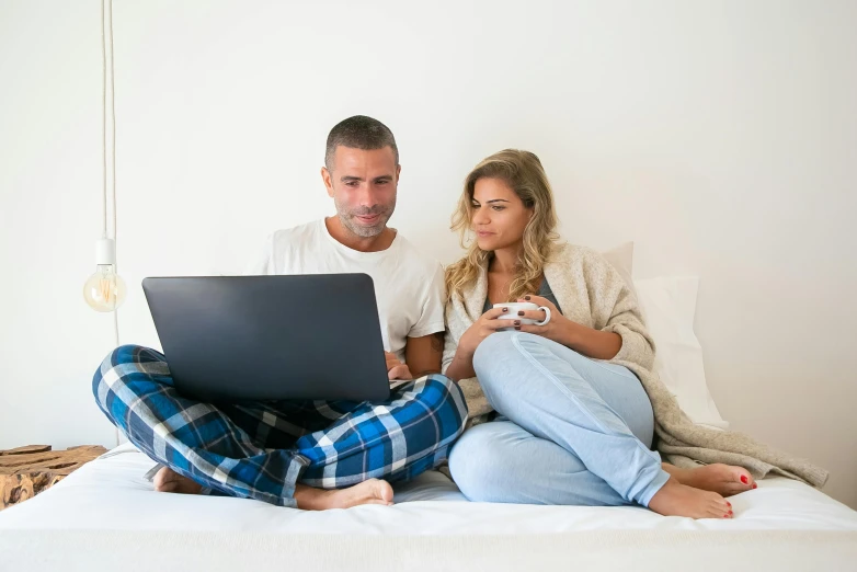 a man and woman sitting on a bed looking at a laptop, by Carey Morris, pexels, figuration libre, casual modern clothing, gaming, raphael lecoste, open plan