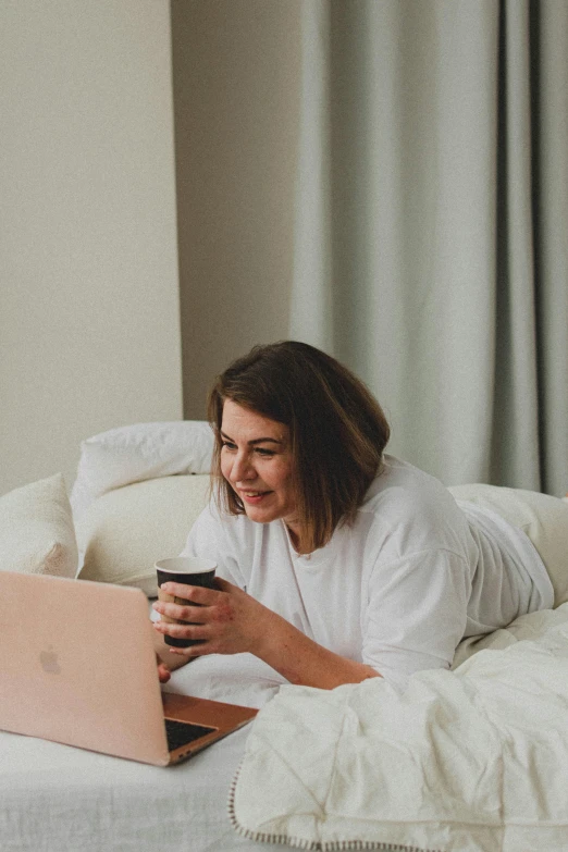 a woman laying on a bed using a laptop computer, pexels contest winner, happening, with a white mug, calmly conversing 8k, low quality photo, everyone having fun