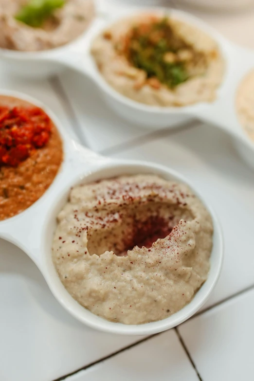 a number of bowls of food on a table, dau-al-set, humus, set against a white background, ballard, relish