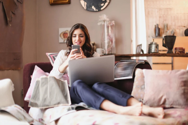 a woman sitting on a couch using a laptop, by Julia Pishtar, trending on pexels, figuration libre, small and cosy student bedroom, goddess checking her phone, curated collections, open plan