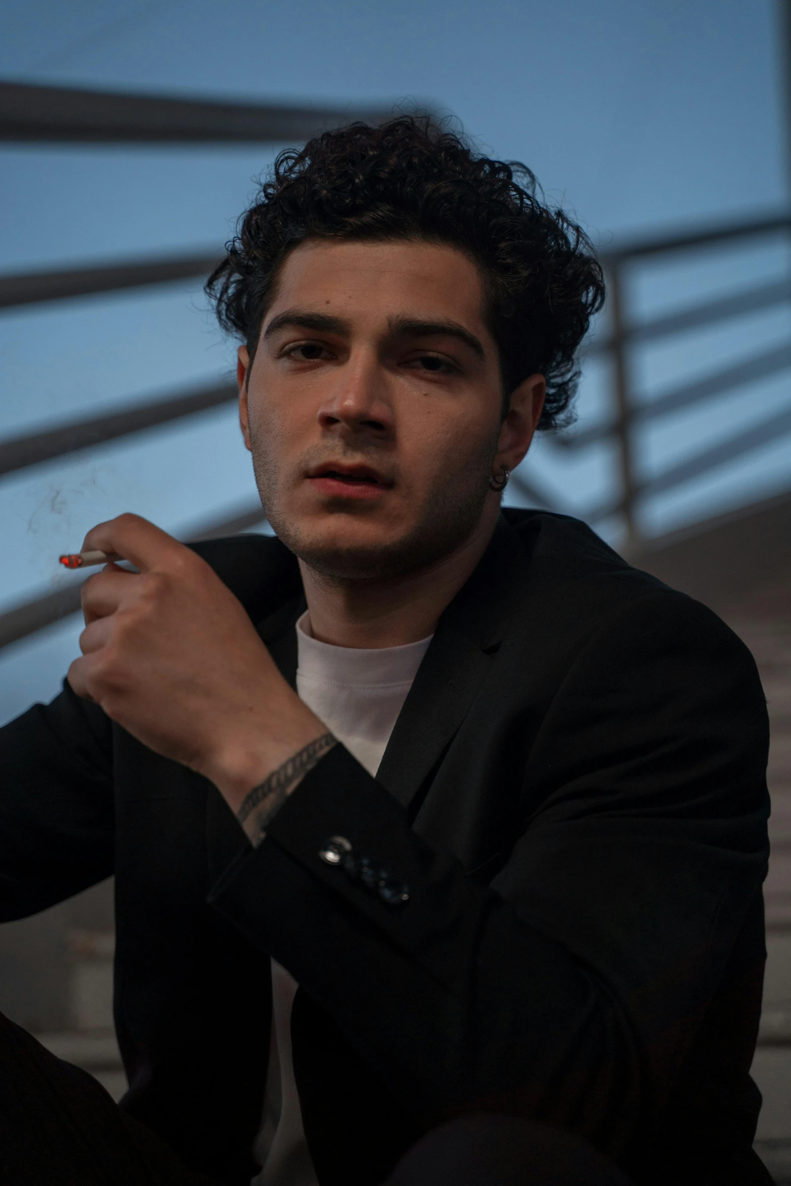 a man sitting on a set of stairs smoking a cigarette, an album cover, by Alejandro Obregón, pexels contest winner, wearing causal black suits, young handsome pale roma, headshot profile picture, asher duran
