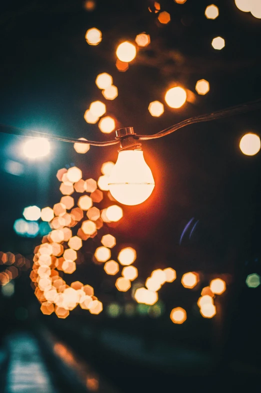 a street filled with lots of lights at night, an album cover, unsplash, light bulb, macro bokeh ”, holiday season, orange teal lighting