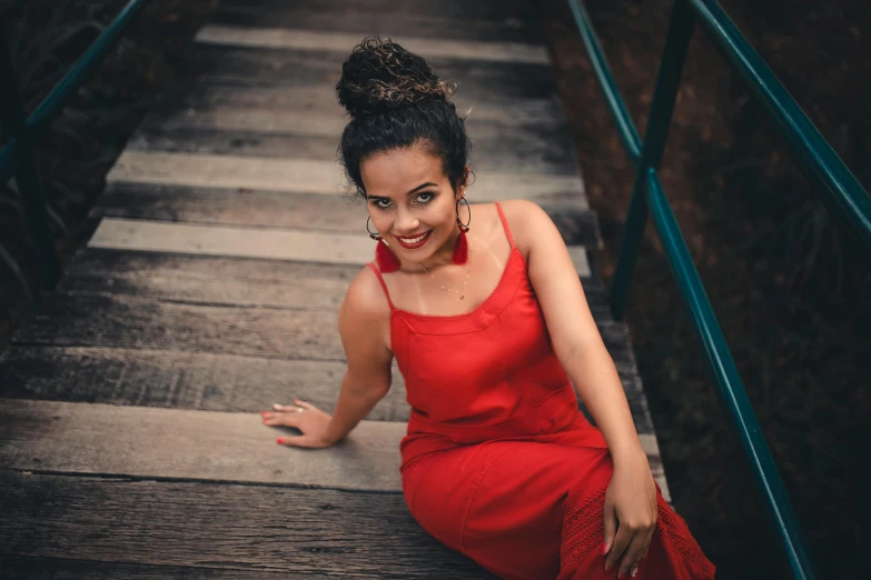 a woman in a red dress sitting on a set of stairs, pexels contest winner, mixed-race woman, smiling for the camera, avatar image, brazilian