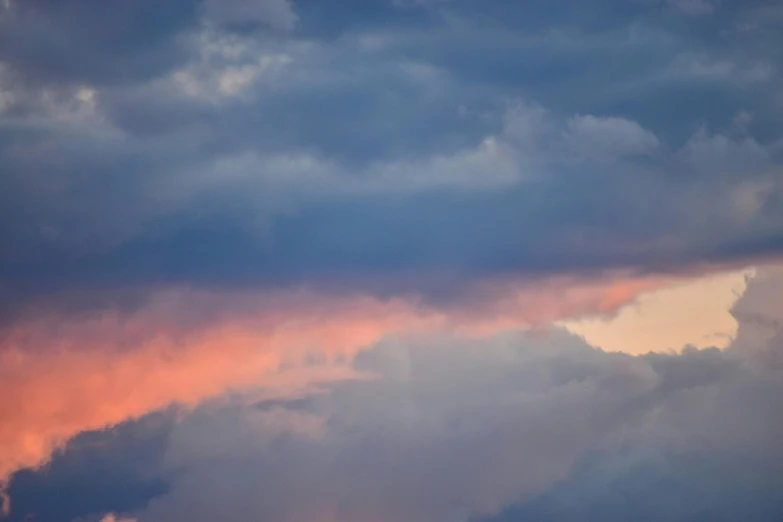 a plane flying through a cloudy sky at sunset, a picture, unsplash, pink and blue, layered stratocumulus clouds, color ( sony a 7 r iv, evening storm