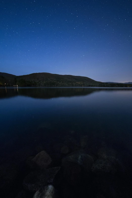 a body of water surrounded by rocks under a night sky, a portrait, new hampshire, mountain lakes, f/1.4, medium-shot