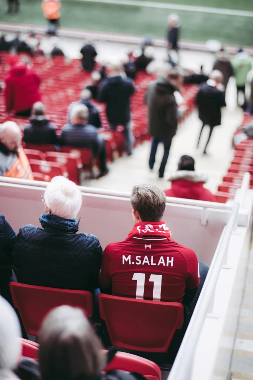 a group of people sitting in a stadium, inspired by Thomas Scholes, unsplash contest winner, mo salah, medium shot of two characters, rear-shot, museum quality photo