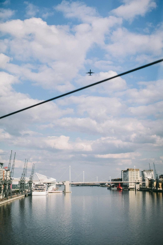 a plane flying over a large body of water, by Lee Loughridge, pexels contest winner, happening, wires hanging above street, boston, trending on vsco, river thames