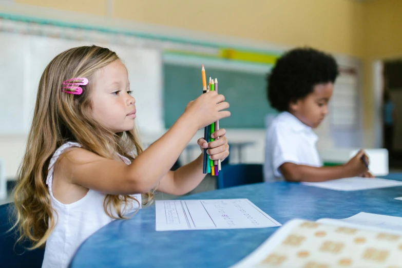 a little girl sitting at a table with a pencil in her hand, pexels contest winner, danube school, holding a staff, varying ethnicities, 15081959 21121991 01012000 4k, thumbnail