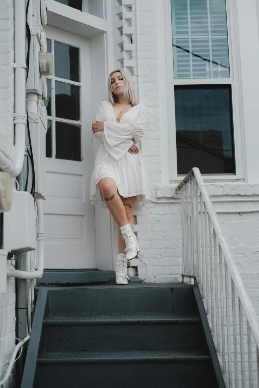 a woman standing on the steps of a house, inspired by Elsa Bleda, pexels contest winner, renaissance, all white, ava max, about to step on you, short dress