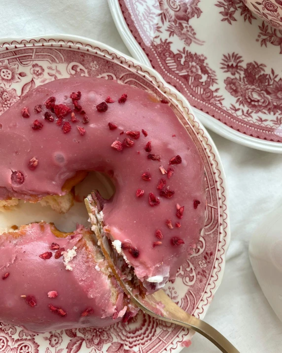 a pink donut sitting on top of a plate, inspired by Henriette Grindat, pomegranate, creamy skin, thumbnail, eating