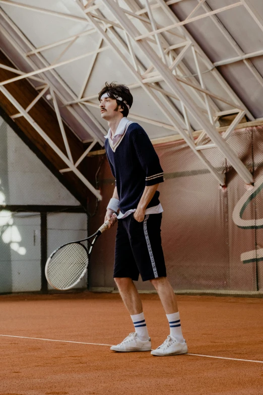 a man standing on a tennis court holding a racquet, inspired by Hans Mertens, unsplash, renaissance, finn wolfhard, wears shorts, wearing a tracksuit, federation clothing