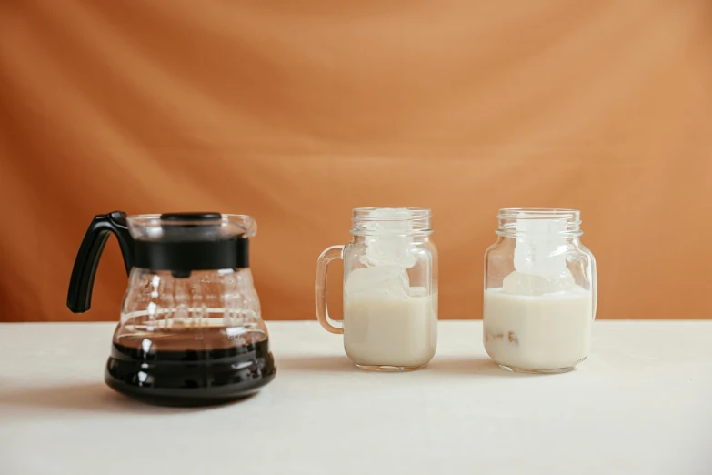 three jars of milk and a pitcher of milk on a table, unsplash, minimalism, coffee machine, background image, iced latte, maple syrup & hot fudge