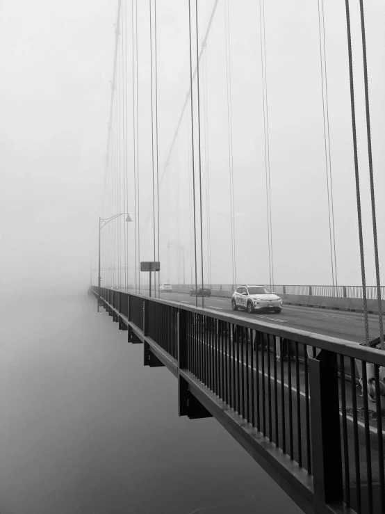 a black and white photo of a bridge on a foggy day, by Peter Madsen, a car, connected with hanging bridge!!, ilustration, professional photo