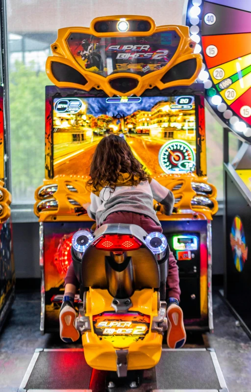 a little girl is playing a video game, by Josh Bayer, pexels, into glory ride, long shot from back, yellow, arcade
