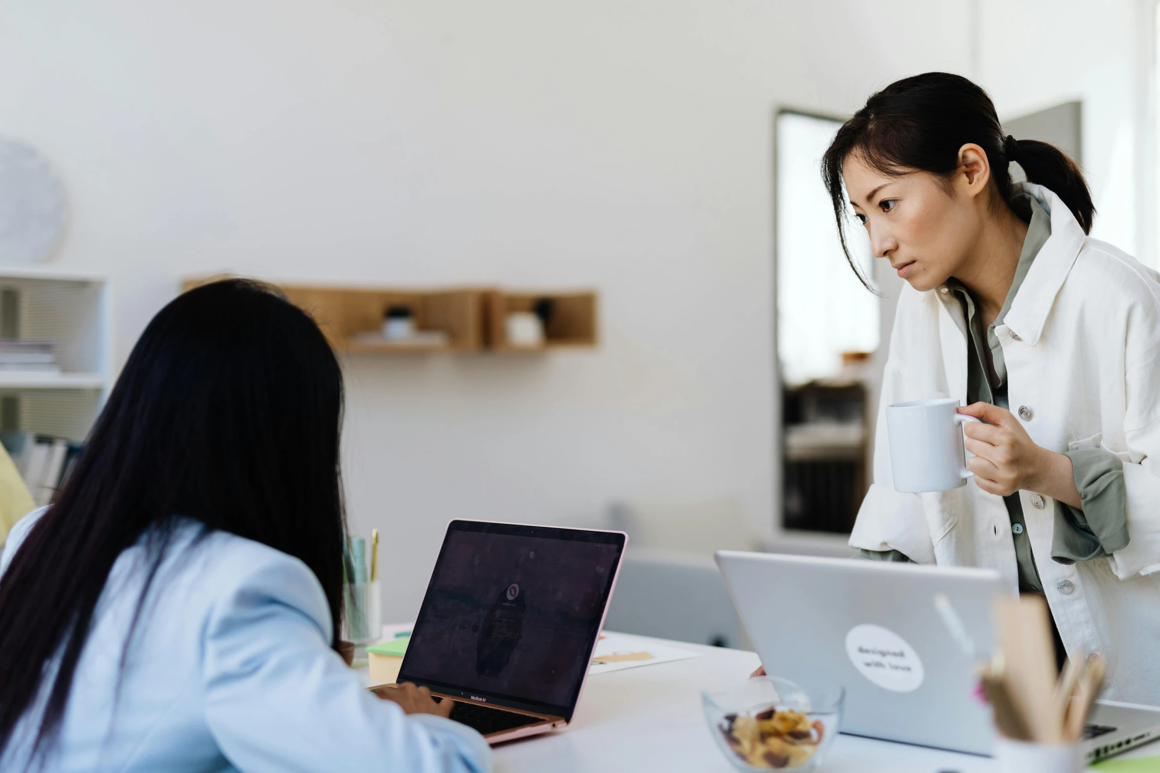 two women sitting at a table with laptops, by Lee Loughridge, trending on pexels, female in office dress, an asian woman, hovering indecision, avatar image