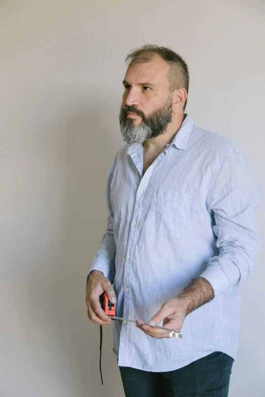 a man with a beard holding a nintendo wii controller, inspired by Paolo Parente, unsplash, hyperrealism, alec soth : : love, holding a crowbar, wearing a linen shirt, press shot