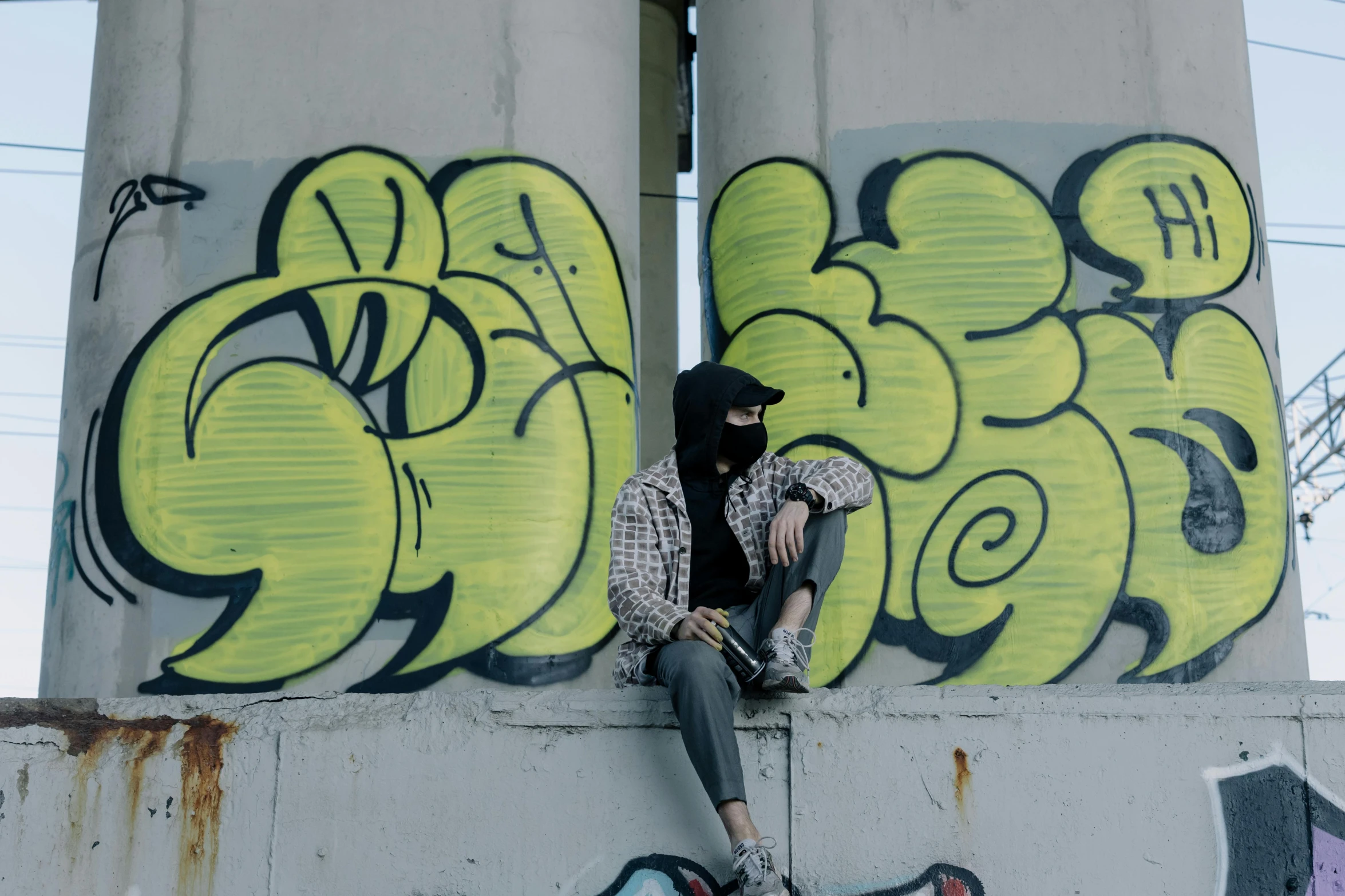 a person sitting on a wall with a skateboard, trending on pexels, graffiti, face covered, avatar image