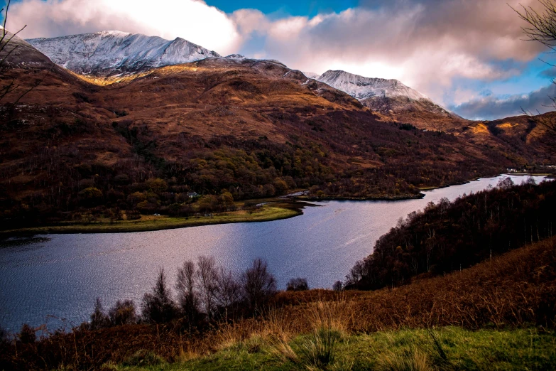 a large body of water sitting on top of a lush green hillside, by Andrew Allan, pexels contest winner, snowy peaks, autumnal, scottish style, thumbnail