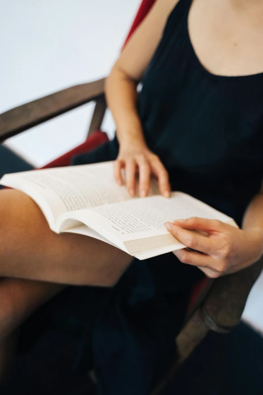 a woman sitting in a chair reading a book, by Carey Morris, pexels contest winner, thigh focus, without text, rectangle, learning