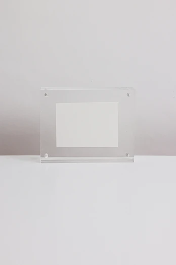 a picture frame sitting on top of a table, by Clifford Ross, visual art, transparent crystal, white frame, rectangle, smol