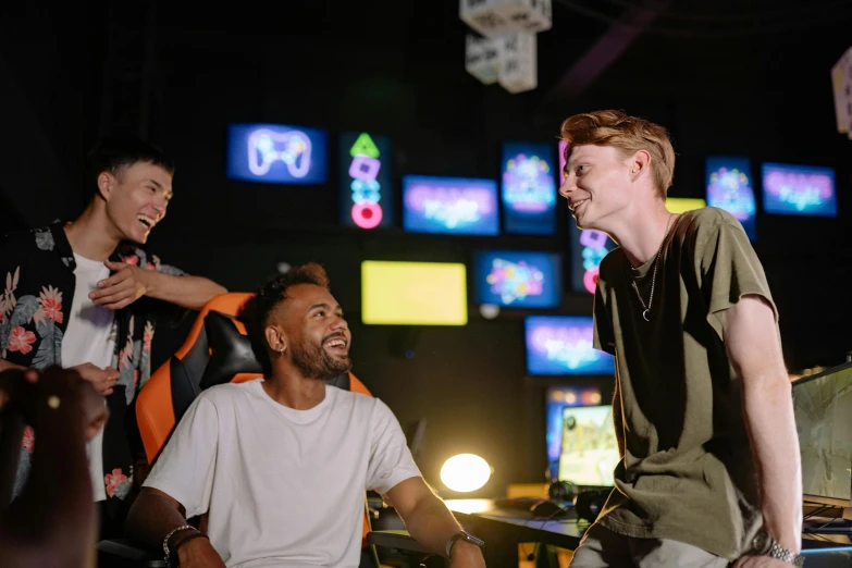 a group of young men standing next to each other, pexels contest winner, interactive art, gaming chair, giggling, neon basement, showing a screen playing tetris