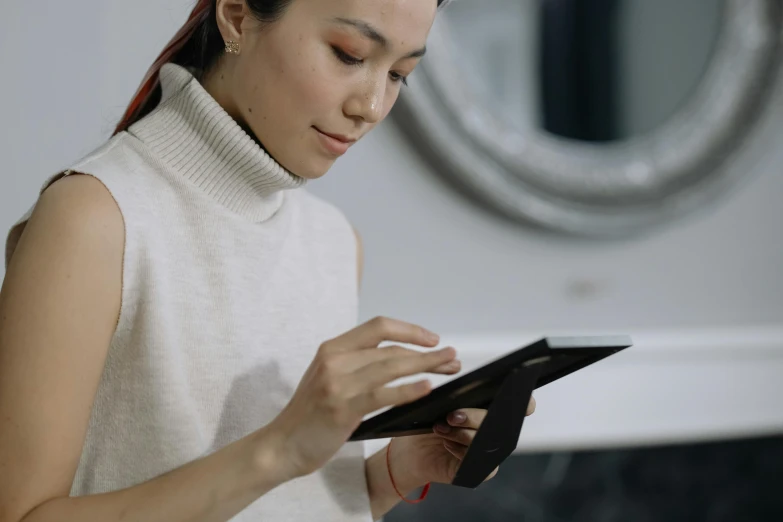 a woman using a tablet computer in front of a mirror, trending on pexels, star trek asian woman, avatar image, smart textiles, bottom angle