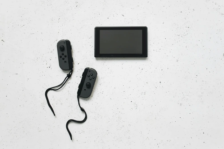 a couple of video game controllers sitting next to each other, a black and white photo, minimalism, nintendo switch, black wired cables, product introduction photo