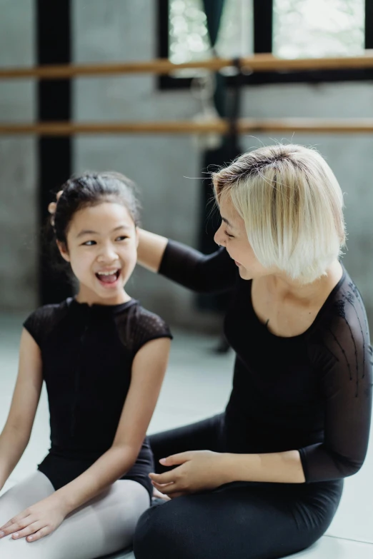 a woman and a little girl sitting on the floor, dancing gracefully, turning her head and smiling, gemma chen, teaching