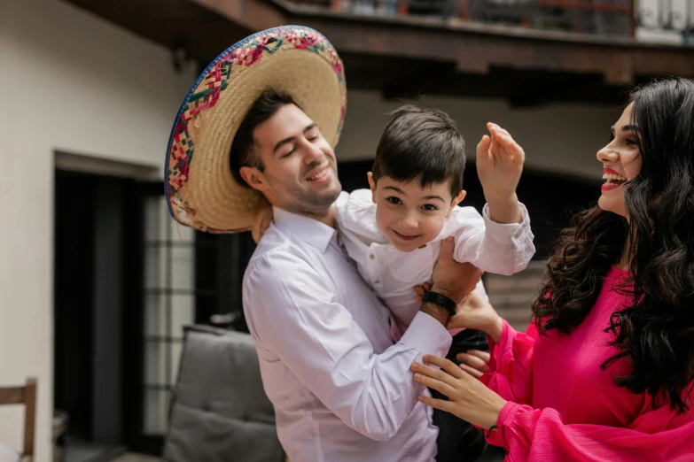 a man standing next to a woman and a child, a colorized photo, by Alejandro Obregón, pexels contest winner, wearing sombrero, being delighted and cheerful, square, avatar image