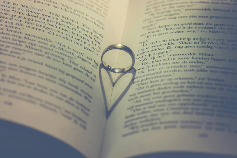 a ring casts a shadow on an open book, pexels, romanticism, (heart), instagram post, low detailed, intertwined