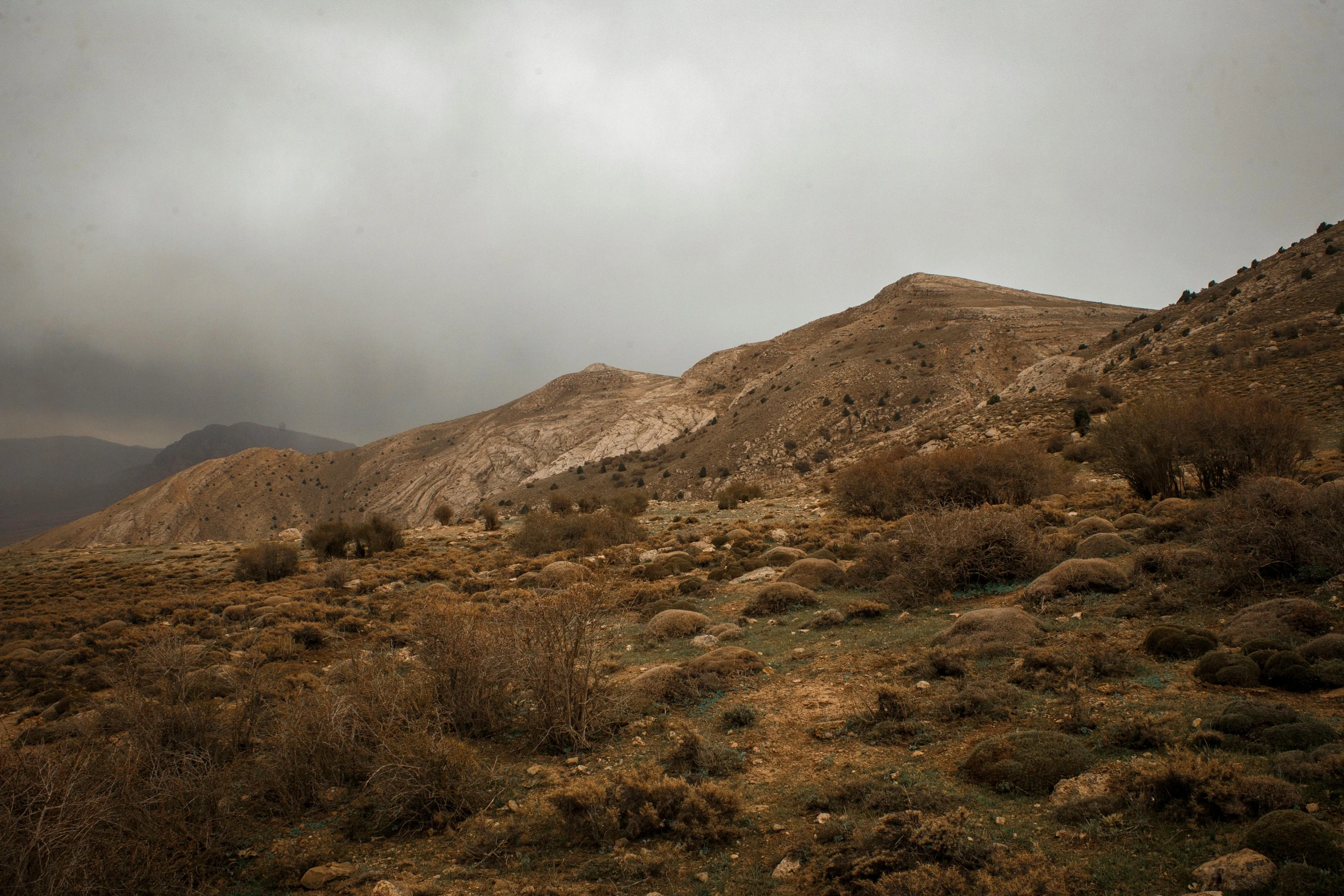 a person standing on top of a hill under a cloudy sky, les nabis, gloomy earthy colors, sayem reza, landscape photo-imagery, caramel. rugged