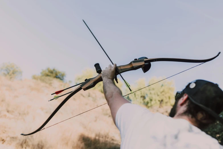 a man holding a bow and arrow in a field, pexels contest winner, ornamental bow, avatar image, middle close up shot, tournament