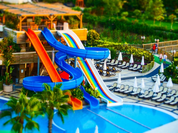 a water slide in the middle of a swimming pool, a tilt shift photo, pexels contest winner, multiple levels, toy photo, rainbow colored, hotel