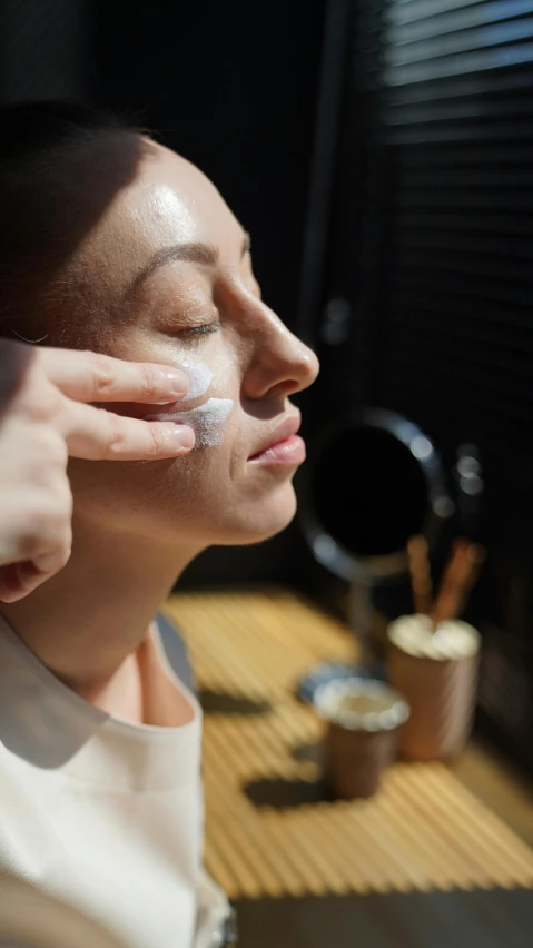 a woman is putting cream on her face, by Jessie Algie, pexels, renaissance, manuka, profile image, behind the scenes photo, thumbnail