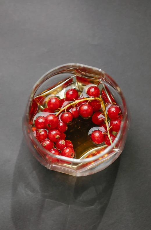 a glass filled with red berries sitting on top of a table, cooking oil, wearing gilded ribes, top - down view, danila tkachenko