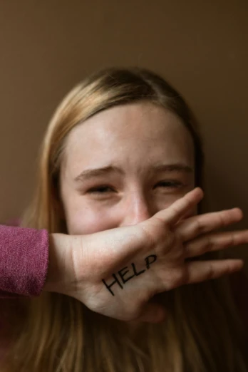 a woman covering her face with her hands, a picture, trending on pexels, antipodeans, saoirse ronan, woman holding sign, 1 7 - year - old boy thin face, scars