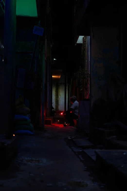 a person riding a scooter down a dark alley, small red lights, manila, man sitting facing away, distant glowing figures