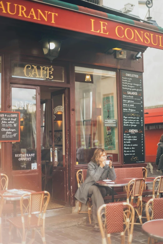 a woman sitting at a table outside of a restaurant, a photo, by Nina Hamnett, trending on unsplash, art nouveau, french village exterior, taken in the 2000s, coffee, square