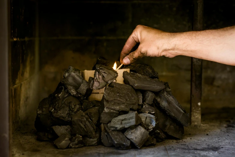 a person lighting a candle in front of a pile of coal, woodfired, profile image, fan favorite, barbecuing chewing gum