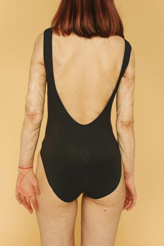 the back of a woman in a black bodysuit, inspired by Vanessa Beecroft, male emaciated, deteriorated, hairy arms, nonbinary model