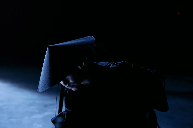 a person sitting on top of a suitcase in the dark, an album cover, inspired by Georges de La Tour, unsplash, conceptual art, plague mask, issey miyake, extremely moody blue lighting, black pointed hat