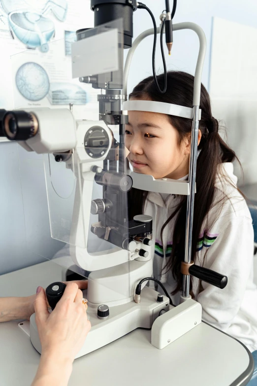 a little girl getting her eye examined by a doctor, a picture, by Jang Seung-eop, shutterstock, hyperrealism, working in her science lab, chinese heritage, detailed : cornea, a very macular woman in white