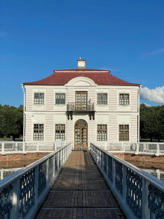 a large white building with a red roof, inspired by Konstantin Vasilyev, neoclassicism, standing on a bridge, view from front, deck, 1 8 th century style