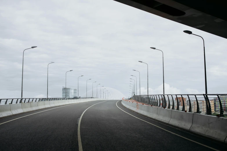 a highway going over a bridge on a cloudy day, an album cover, unsplash, happening, neo norilsk, bjarke ingels, empty streetscapes, headlights turned on